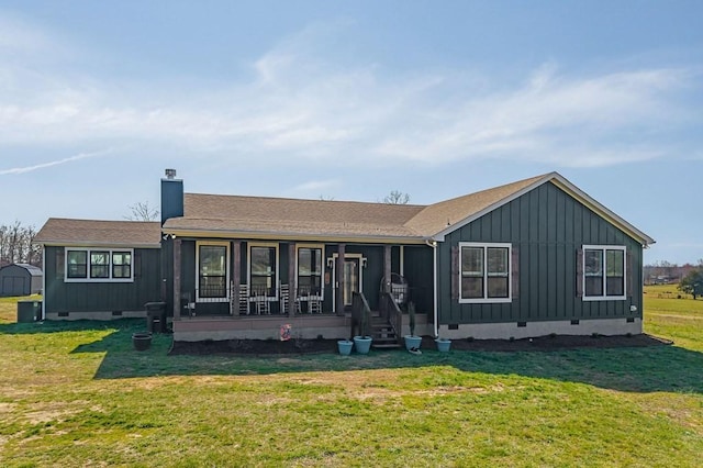 back of property featuring a yard, covered porch, a chimney, crawl space, and board and batten siding