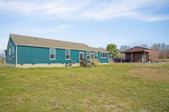 rear view of property with crawl space, an outbuilding, and a yard