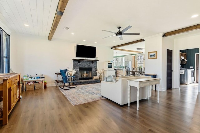 living area featuring ceiling fan, beam ceiling, a stone fireplace, and wood finished floors