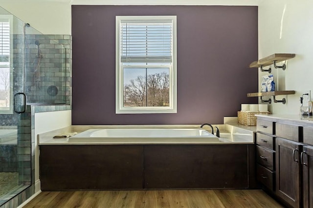 full bathroom with a shower stall, a bath, and wood finished floors