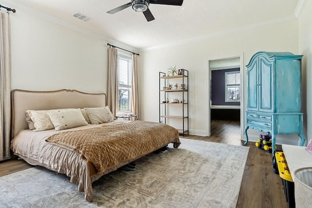 bedroom with visible vents, ornamental molding, a ceiling fan, wood finished floors, and baseboards