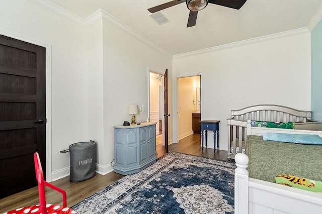 bedroom with visible vents, baseboards, wood finished floors, and crown molding