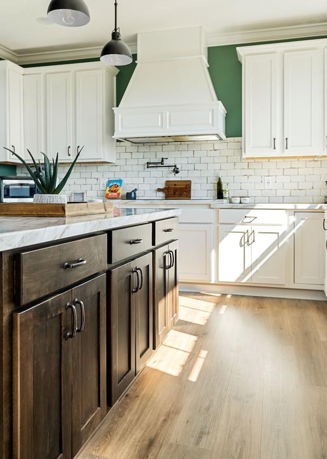 kitchen with dark brown cabinetry, white cabinets, premium range hood, and light wood-type flooring