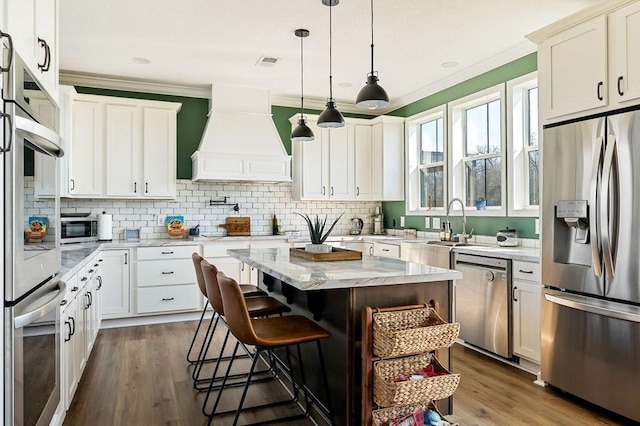 kitchen featuring a breakfast bar area, ornamental molding, dark wood-style floors, custom exhaust hood, and stainless steel appliances