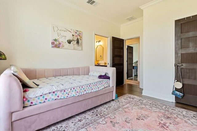 bedroom with visible vents, wood finished floors, baseboards, and ornamental molding