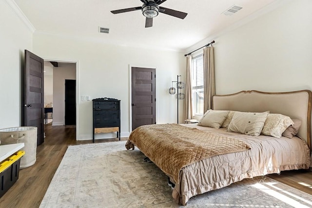 bedroom with crown molding, wood finished floors, visible vents, and ceiling fan