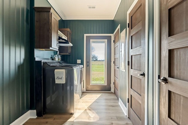 laundry room with visible vents, light wood-style flooring, cabinet space, ornamental molding, and washing machine and dryer