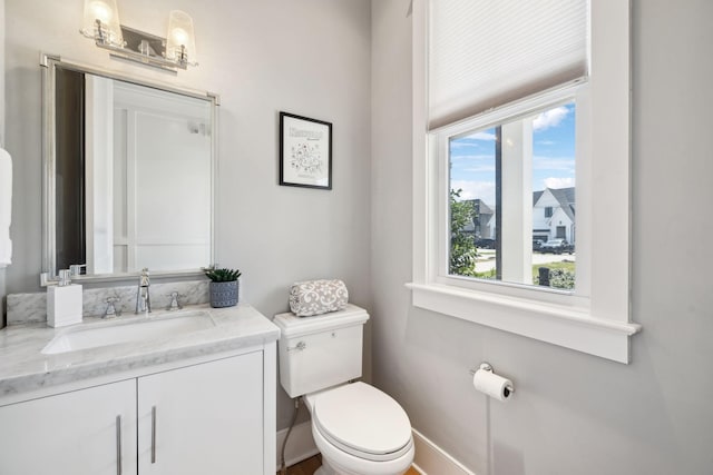 bathroom with baseboards, toilet, and vanity