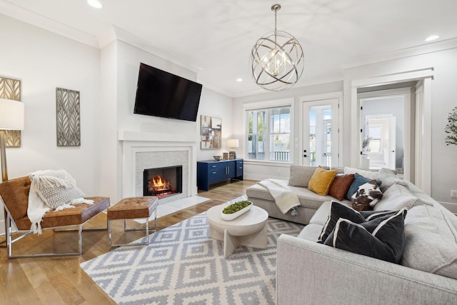 living room with a fireplace with flush hearth, light wood-style floors, and crown molding