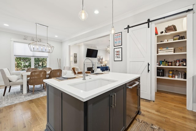 kitchen with light wood-style flooring, a sink, light countertops, a barn door, and open floor plan