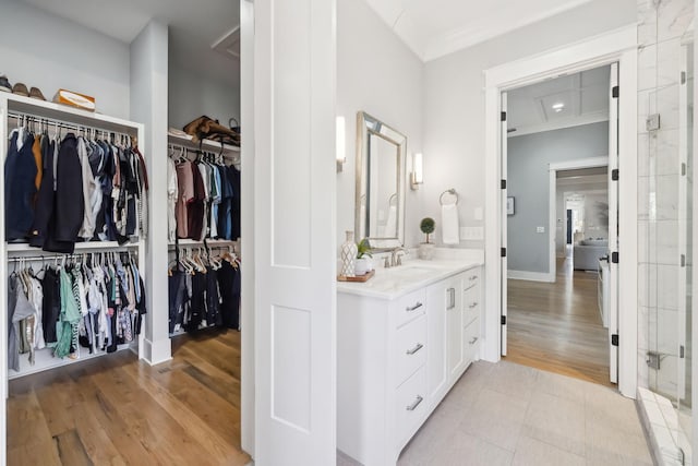 full bath featuring a spacious closet, baseboards, ornamental molding, wood finished floors, and vanity