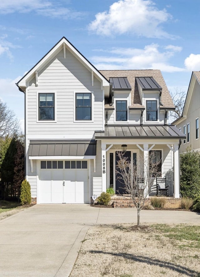 view of front of home with a porch, concrete driveway, metal roof, a garage, and a standing seam roof