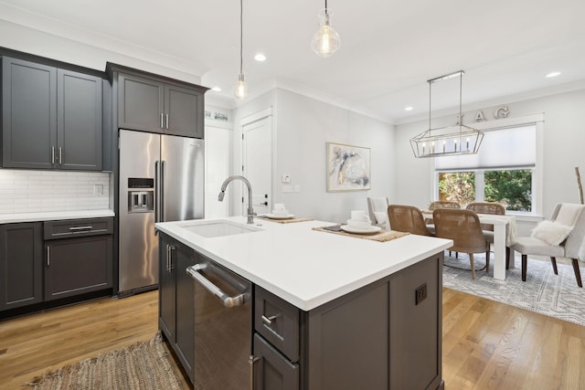 kitchen with ornamental molding, a sink, light countertops, appliances with stainless steel finishes, and backsplash