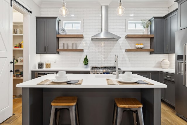 kitchen with open shelves, wall chimney range hood, high quality fridge, and a kitchen breakfast bar