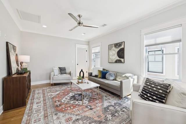 living room with visible vents, baseboards, wood finished floors, and ornamental molding