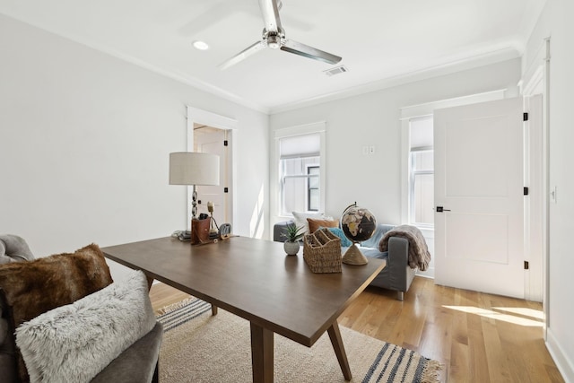 office with a ceiling fan, visible vents, light wood finished floors, and ornamental molding