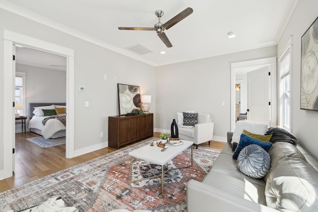 living room featuring a wealth of natural light, baseboards, wood finished floors, and crown molding