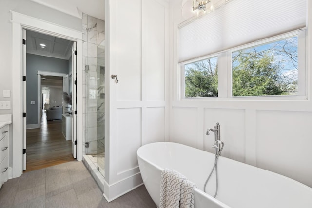 bathroom featuring a shower stall, a decorative wall, crown molding, a soaking tub, and vanity