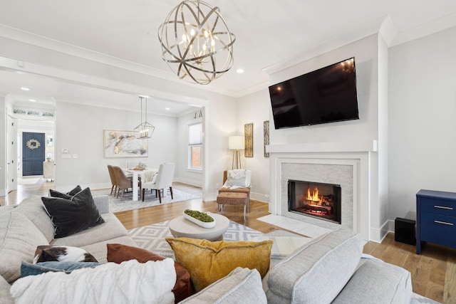 living area featuring a chandelier, ornamental molding, baseboards, and wood finished floors