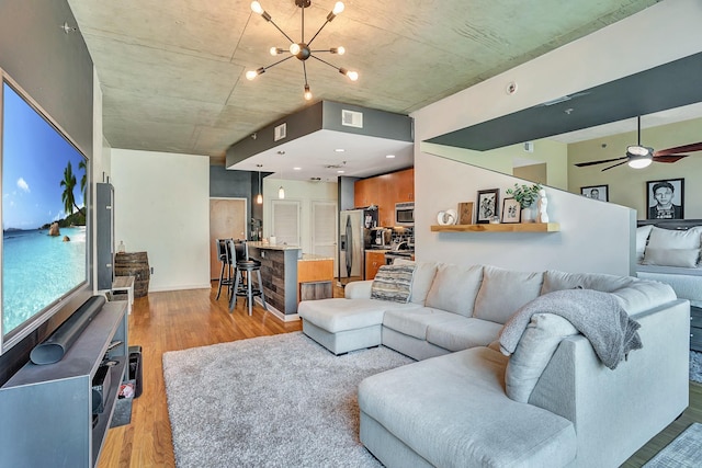 living area with visible vents, light wood-style flooring, and ceiling fan with notable chandelier