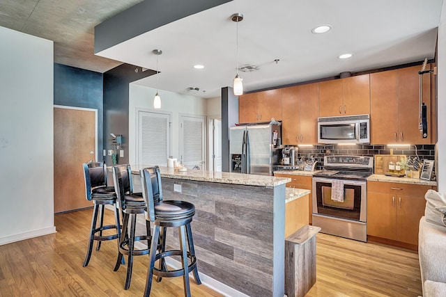 kitchen featuring light stone counters, tasteful backsplash, light wood finished floors, and stainless steel appliances