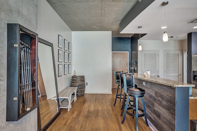 bar with hanging light fixtures and wood finished floors