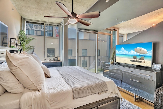 bedroom featuring a ceiling fan, a wall of windows, access to outside, and wood finished floors