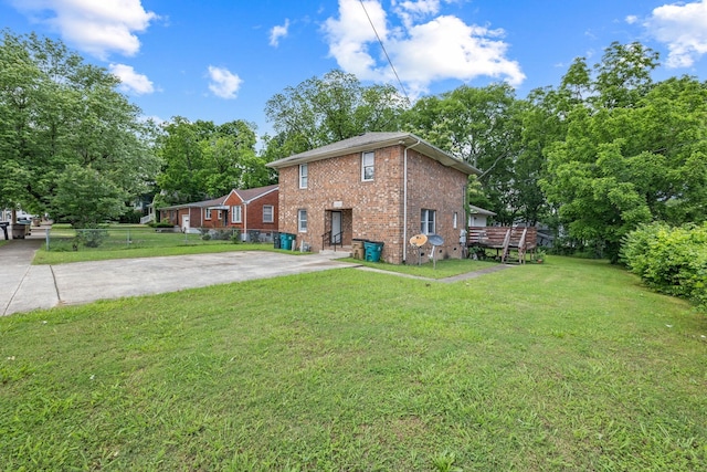 rear view of house featuring a yard, brick siding, and driveway