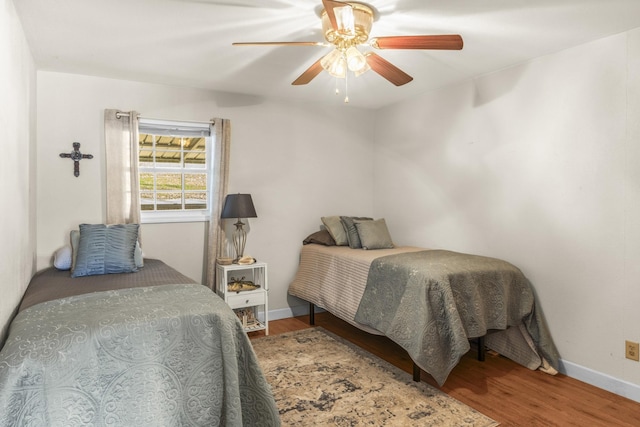 bedroom featuring baseboards, wood finished floors, and a ceiling fan