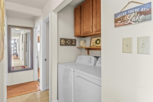 laundry area with light tile patterned flooring, cabinet space, and washer and clothes dryer