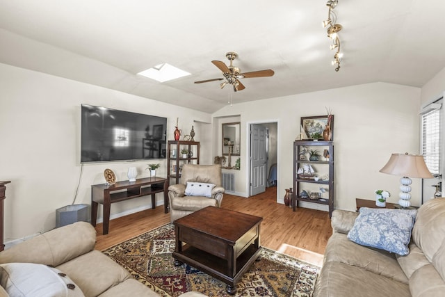 living room with a ceiling fan, lofted ceiling with skylight, wood finished floors, and visible vents