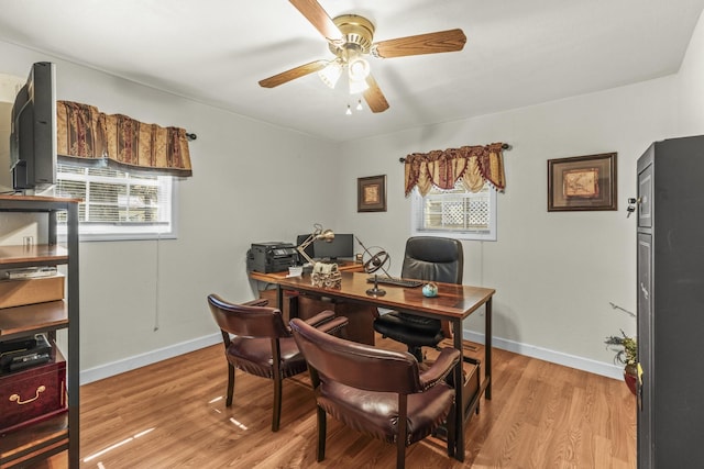 office featuring baseboards, light wood-style floors, and a ceiling fan