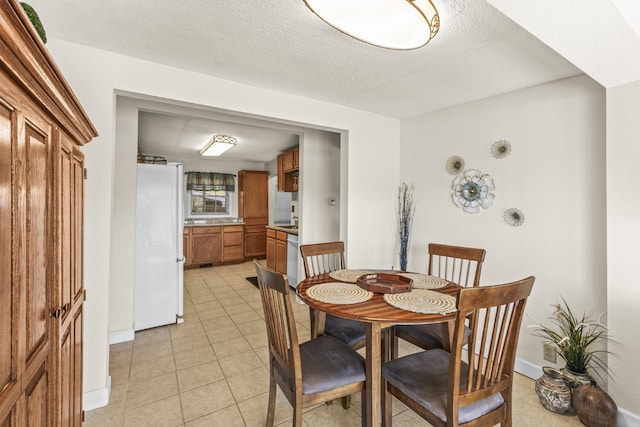 dining space with baseboards, a textured ceiling, and light tile patterned flooring