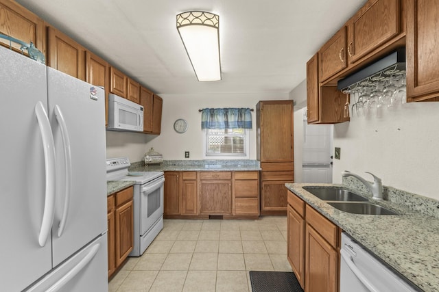 kitchen featuring a sink, white appliances, brown cabinetry, and light tile patterned floors