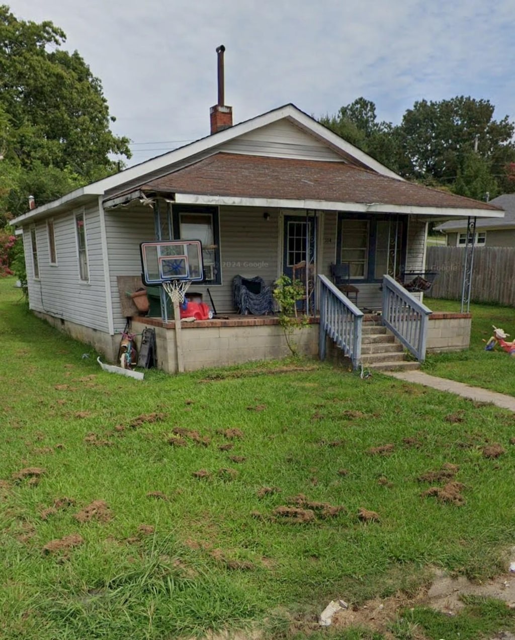 view of front of house featuring crawl space, a chimney, a porch, and a front lawn