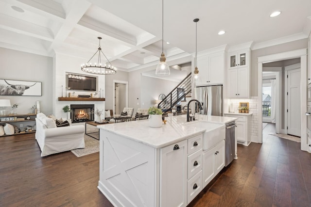 kitchen featuring dark wood finished floors, appliances with stainless steel finishes, a fireplace, and a sink