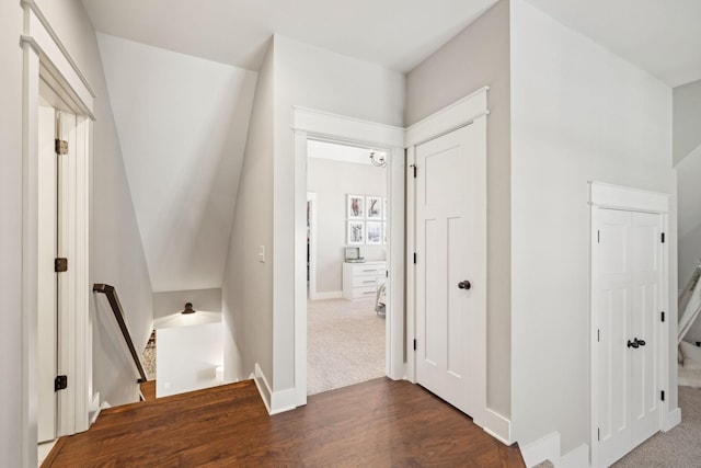 hall featuring dark wood finished floors, an upstairs landing, and baseboards