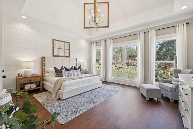 bedroom featuring dark wood-type flooring, a notable chandelier, recessed lighting, and a raised ceiling