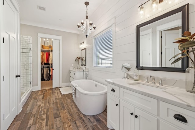 bathroom with visible vents, wood finished floors, a stall shower, a freestanding tub, and a sink