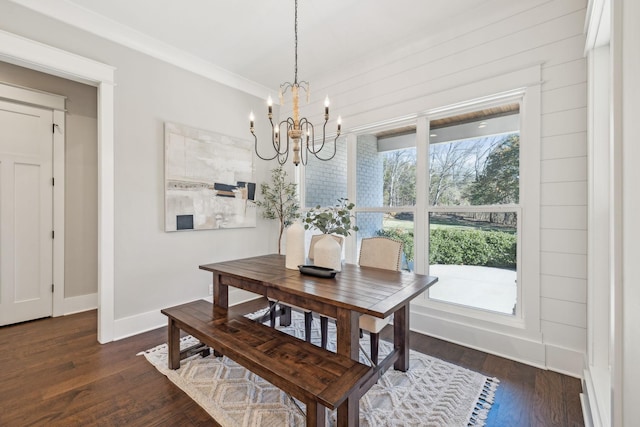 dining space with dark wood finished floors, a notable chandelier, and baseboards