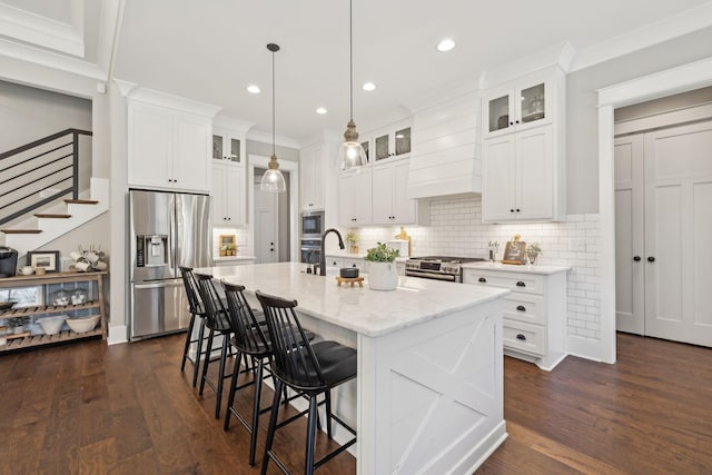 kitchen featuring a breakfast bar area, a center island with sink, dark wood-type flooring, white cabinets, and appliances with stainless steel finishes