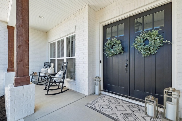 property entrance with brick siding and a porch