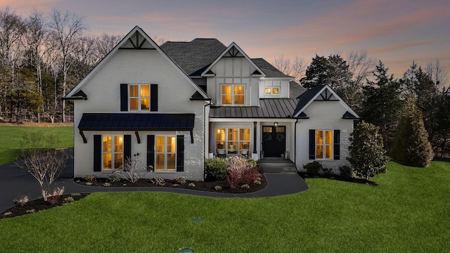 modern farmhouse with metal roof, a lawn, brick siding, and a standing seam roof