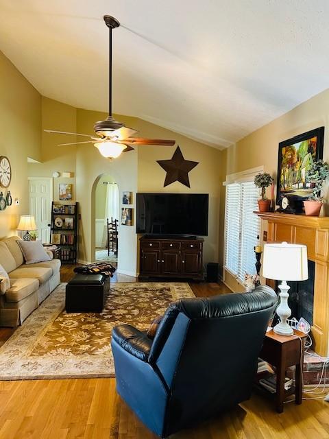 living room featuring arched walkways, ceiling fan, lofted ceiling, and wood finished floors