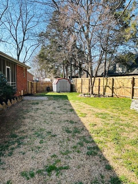 view of yard featuring an outbuilding, a storage shed, and a fenced backyard