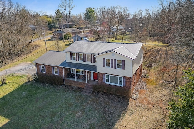 traditional-style house with metal roof, a front lawn, and fence