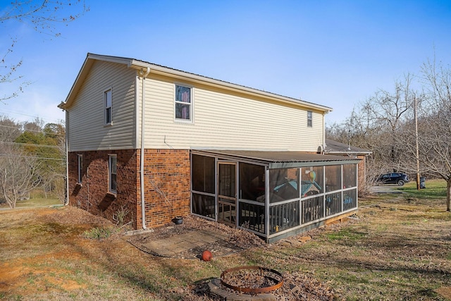 rear view of property with brick siding and a sunroom