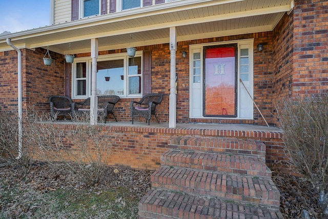 entrance to property with brick siding and a porch