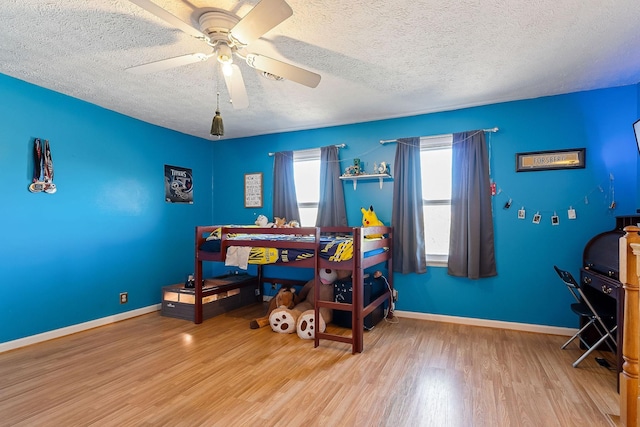 bedroom with a textured ceiling, baseboards, and wood finished floors