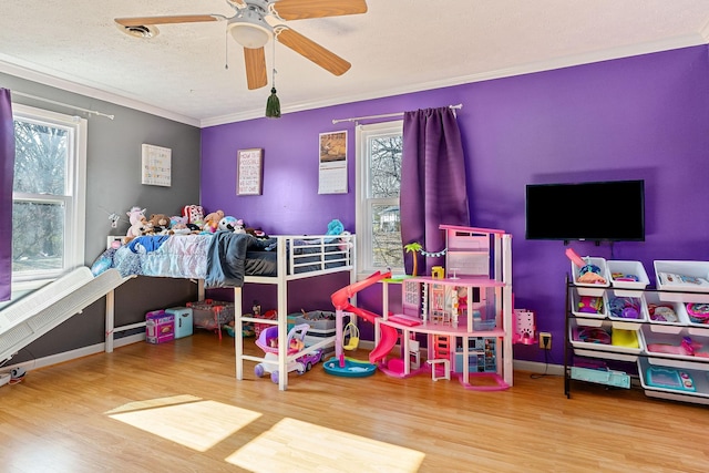 bedroom with baseboards, ornamental molding, wood finished floors, a textured ceiling, and a ceiling fan